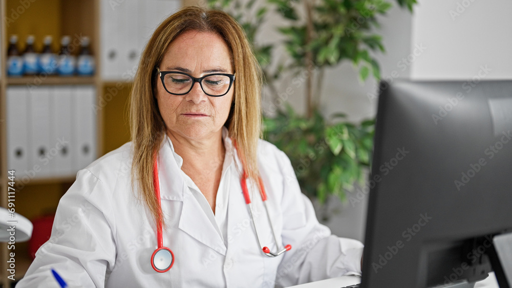 Canvas Prints Middle age hispanic woman doctor using computer writing medical report at the clinic