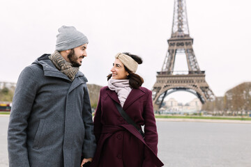 Lovely young european couple walking through paris. Two millennial people visiting Eiffel Tower...