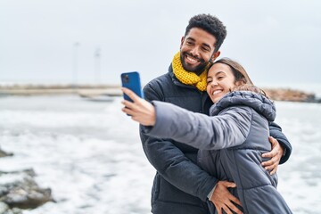 Man and woman couple smiling confident make selfie by smartphone at seaside - obrazy, fototapety, plakaty