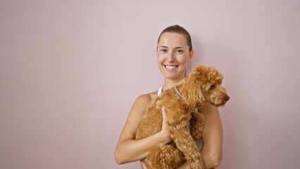 Young caucasian woman with dog smiling hugging over isolated pink background