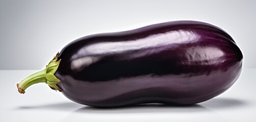  a purple eggplant on a white surface with a green stalk sticking out of the end of the eggplant.