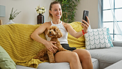 Young caucasian woman with dog doing video call sitting on the sofa at home