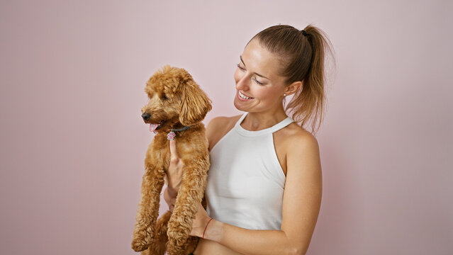Young caucasian woman with dog smiling hugging over isolated pink background