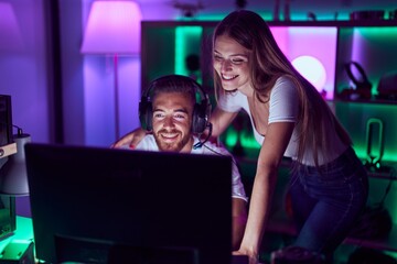 Young couple playing video games smiling with a happy and cool smile on face. showing teeth.