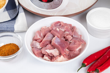 Prepared meat and other ingredients ingredients for cooking pilaf in modern multi cooker in kitchen on a table. Cooking pilau with meat in multicooker.