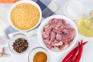 Prepared ingredients for cooking pilaf in modern multi cooker in kitchen on a table. Cooking pilau with meat in multicooker.