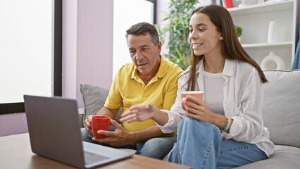 Heartwarming father-daughter moment, relaxed family indoor drinking coffee, smiling, chatting on...