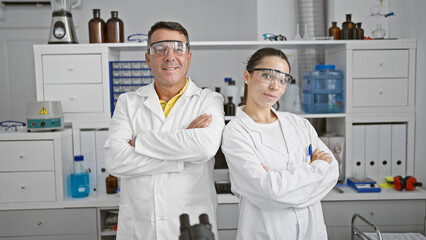 Smiling man and woman scientists with crossed arms in lab, happy partners in the world of research