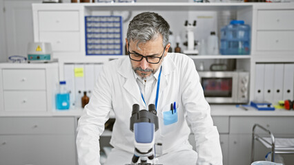 Attractive grey-haired young hispanic man, a dedicated scientist, working intently on a medical...