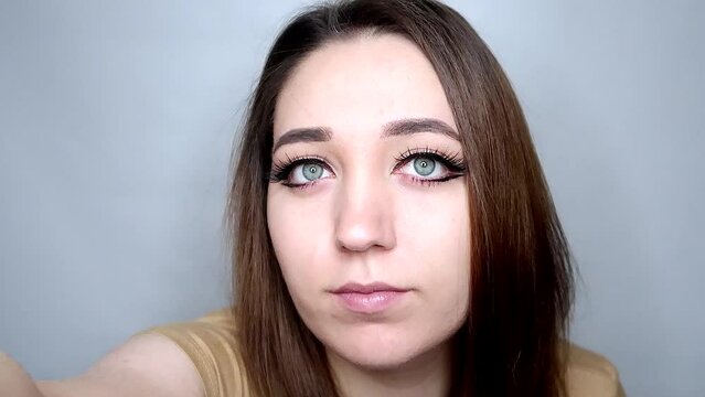 Beauty blogger with long eyelashes zooms out on camera. Lady evaluates harmony of beauty blogger entire image Concept ideal angle for filming video is so important for beauty blogger as long eyelashes