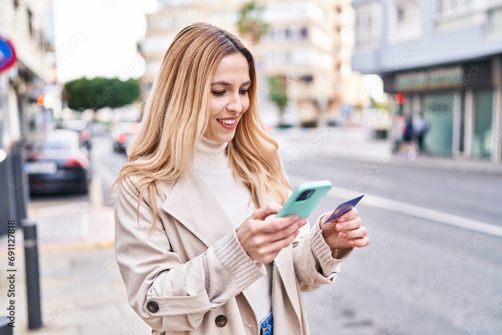 Poster young blonde woman using smartphone and credit card at street