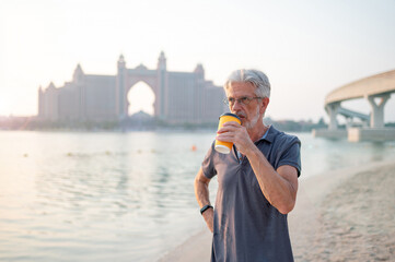 Senior visiting Palm Jumeirah in Dubai standing on the public beach