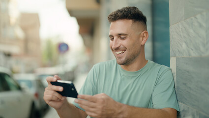 Young hispanic man smiling confident watching video on smartphone at street