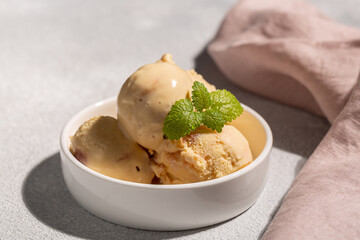 A balls of peach ice cream with a mint leaf in a beautiful creamer