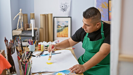 Passionate young latin artist, diligently immersed in his drawing lesson in art studio, crafting...