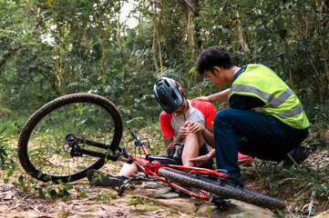 Mountain Bike Accident Cyclist Falls and Suffers Injury in Practice Activities Cycling Sports in Natural Park, Urgent Aid Required and Receive Care from First Aid Staff Assistant.