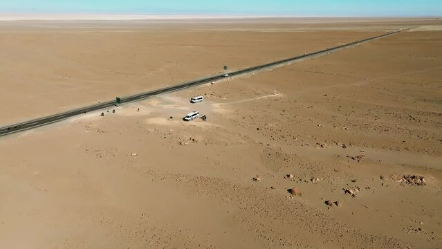 Turistas em furg&atilde;o parados no meio do deserto com apenas uma estrada &agrave; vista.