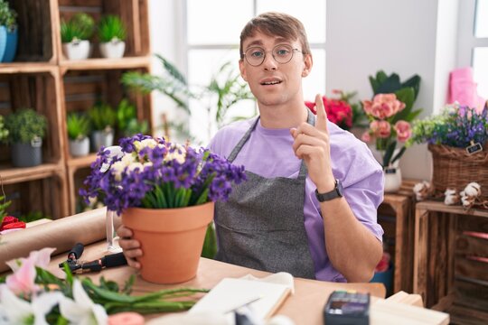 Caucasian blond man working at florist shop pointing finger up with successful idea. exited and happy. number one.
