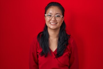 Asian young woman standing over red background with a happy and cool smile on face. lucky person.