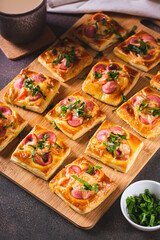 Snack mini pizza with sausages, tomato and cheese on a wooden board vertical view