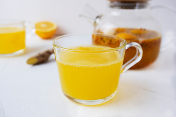 Sea buckthorn tea with orange and ginger in glass cups on a light background. Herbal vitamin tea