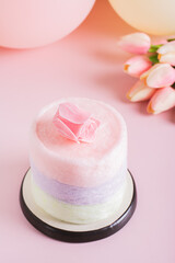 Cotton candy cake, flowers, candles and balloons for party on table vertical view