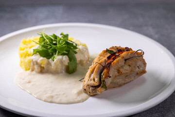 turkey roll filled with spinach and ham served with mashed potatoes and cream sauce