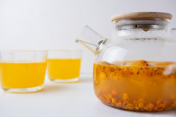 Sea buckthorn tea with orange and ginger in glass cups on a light background. Herbal vitamin tea