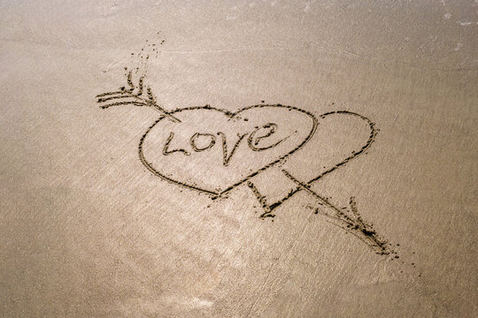 drawing in sand in form of two hearts and inscription love