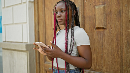 Cool braids! stunning black african american woman seriously concentrating on her smartphone,...