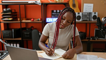 Passionate african american woman musician taking notes while engaging in a serious video call at...