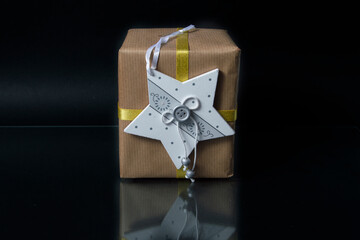 gift box with wooden star on black background and glass projecting its reflection