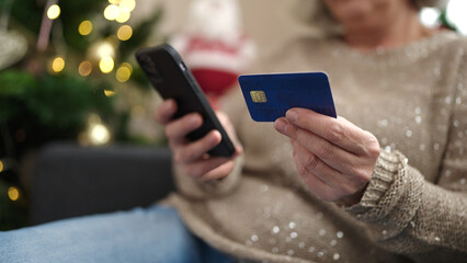 Middle age woman with grey hair doing christmas online shopping with smartphone at home