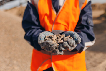 Worker engineer hold gravel in hand checks quality, sand quarry. Industrial construction site...