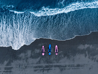 Aerial top view Group of friends in wetsuit going to surf at black beach. Lifestyle Extreme Surfer winter surfing in North ocean Kamchatka Russia
