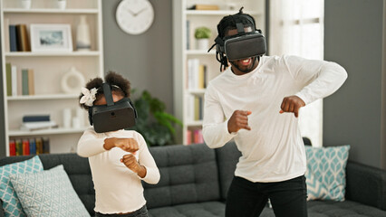 African american father and daughter playing video game using virtual reality glasses at home