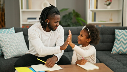 African american father and daughter smiling confident sitting on sofa drawing high five at home
