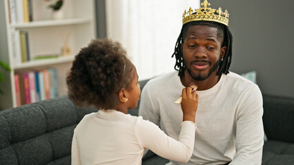 African american father and daughter wearing king crown playing with makeup at home