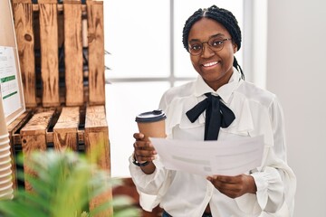 African american woman business worker reading document drinking coffee at office