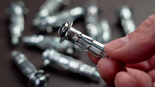 Anchor drywall fastener in the hand of a mechanic in a workshop close up. Industry tool concept
