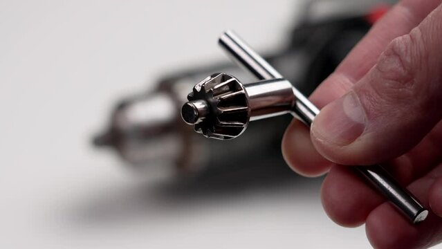 Drill chuck key in a repairman hand in a workshop close up
