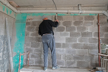 The builder is checking the evenness of the wall.