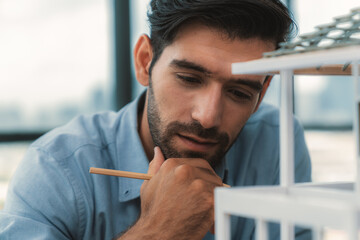 Closeup portrait of smart caucasian engineer face inspect house model while thinking about building...