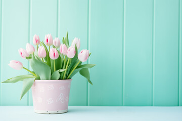 Pink Tulips in Pink Pot Against Mint Wall. Pastel Floral Arrangement for a Springtime Background with Copy Space.