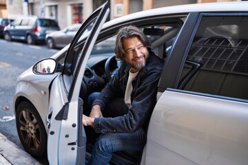 Middle age man smiling confident opening car door at street