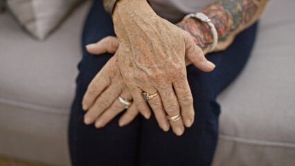 Relaxed senior woman sitting comfortably on living room sofa, resting hands together at cozy home...