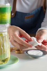 Kitchen hacks: Woman using cotton pad to prevent oil from running down. Step 1