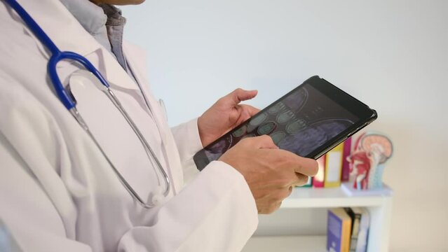 Experience the world of healthcare as a dedicated doctor in a hospital reviews a neuro image on a tablet, exploring test results. Immerse yourself in the concept of clinical medical care, neuroimaging