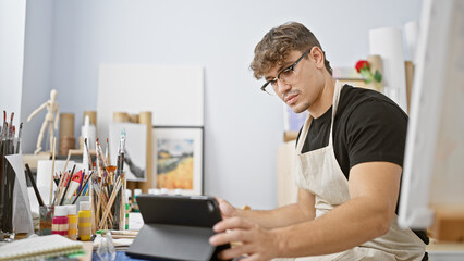 Attractive young hispanic man, a committed art student, fervently engrossed in drawing on his...