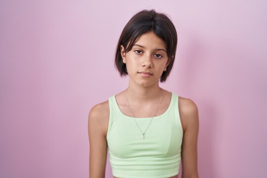 Young girl standing over pink background looking sleepy and tired, exhausted for fatigue and hangover, lazy eyes in the morning.